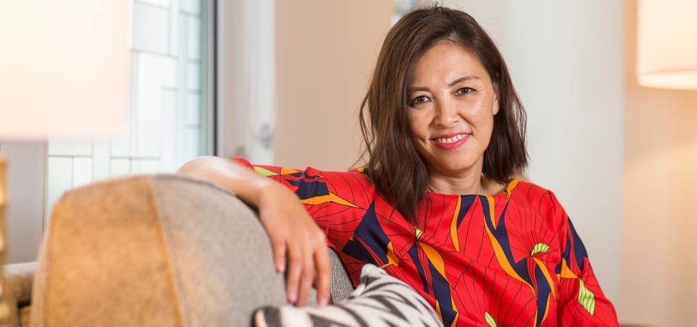 A woman sitting back in an armchair in a bright living room.